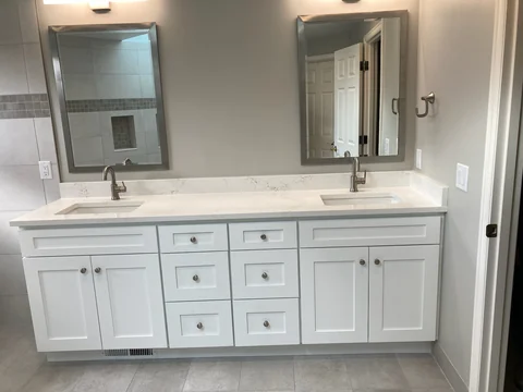 Finished white double sink bathroom vanity with shaker doors and quartz countertop