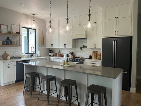 Finished white shaker kitchen with contrasting dark island and pendant lights